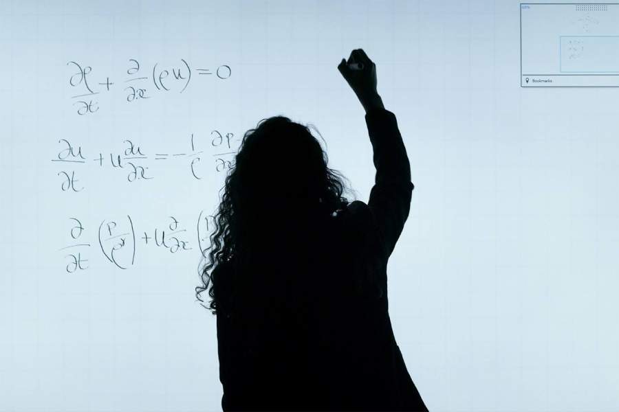 An image of a woman confidently solving a math problem on a whiteboard, demonstrating effective maths study strategies. 